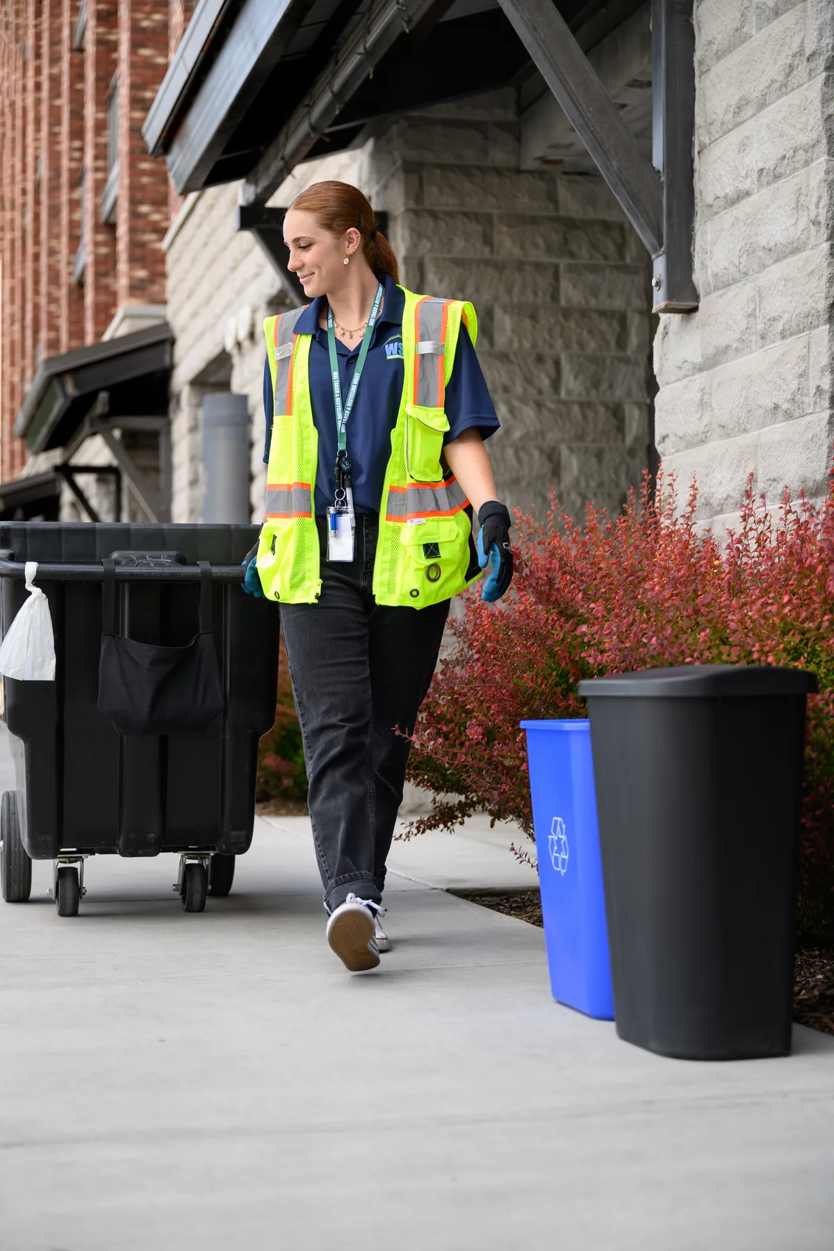 A WSI associate beside trash and recycling bins at an apartment community