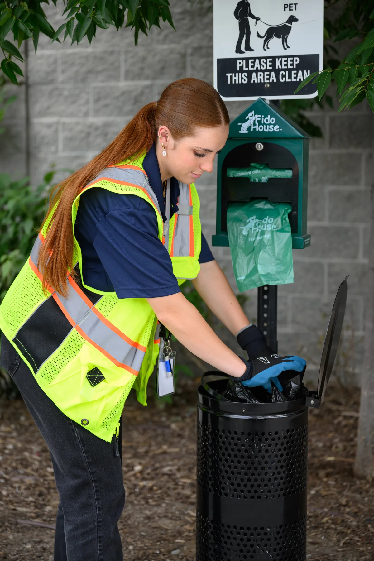 A WSI associate changing the waste bag at a community pet waste station